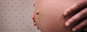 pregnant woman holding her belly in an exam room in Bozeman Clinic in Bozeman, MT