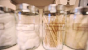 four jars containing medical swabs on an exam room counter